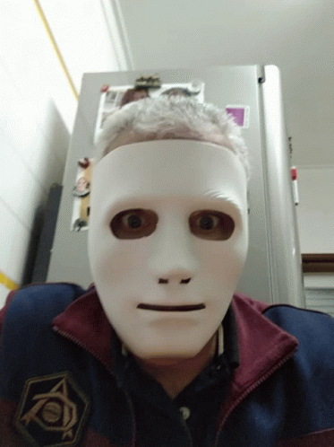 A Man Wearing A White Mask Is Standing In Front Of A Fridge That Has A Picture Of A Cat On It GIF