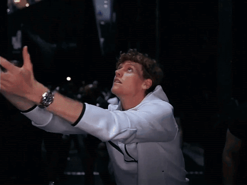 A Man Wearing A White Nike Jacket Holds A Tennis Ball In His Hand GIF