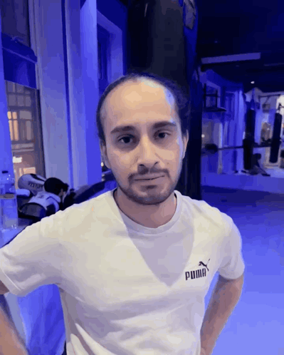 A Man Wearing A White Puma T-Shirt Stands In A Gym GIF