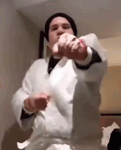 A Man Wearing A White Robe And A Black Hat Is Holding A Piece Of Paper In His Hands . GIF