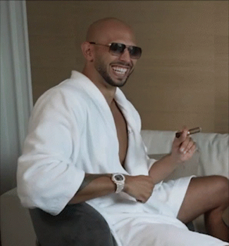 A Man Wearing A White Robe And Sunglasses Is Smiling And Smoking A Cigar GIF