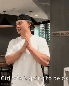 A Man Wearing A White Shirt And A Black Hat Is Standing In Front Of A Sign That Says Bistro To Go . GIF