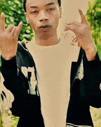 A Man Wearing A White Shirt And A Black Jacket With The Letter T On It Is Giving The Middle Finger GIF