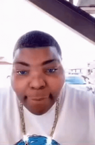 A Man Wearing A White Shirt And A Chain Is Making A Funny Face . GIF