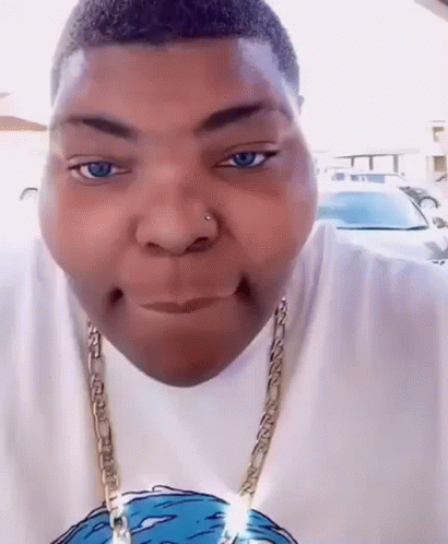 A Man Wearing A White Shirt And A Gold Chain Is Making A Face . GIF