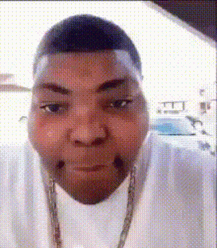 A Man Wearing A White Shirt And A Gold Chain Is Making A Face . GIF