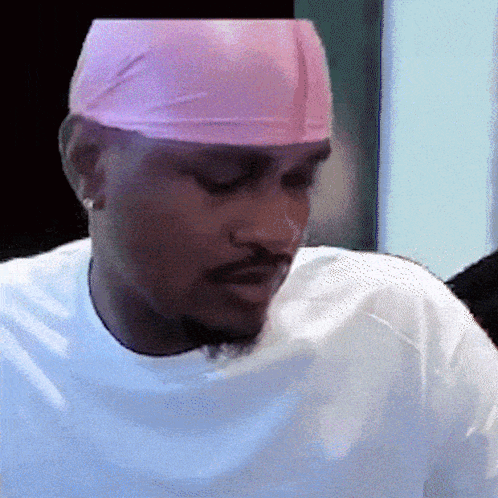 A Man Wearing A White Shirt And A Pink Headband Looks Down GIF