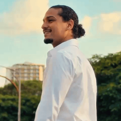 A Man Wearing A White Shirt And A Ponytail Is Smiling . GIF