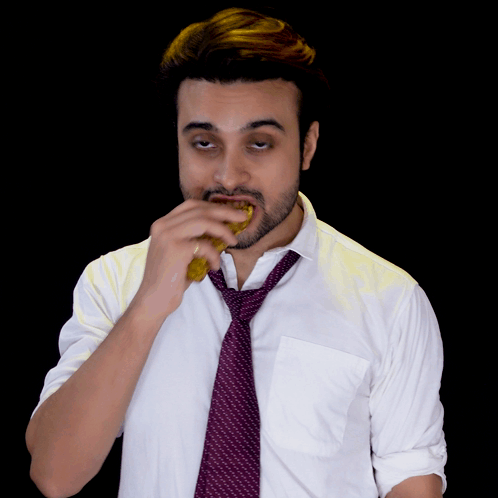 A Man Wearing A White Shirt And A Purple Tie Eating Something GIF