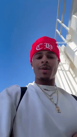 A Man Wearing A White Shirt And A Red Beanie With The Letter H On It GIF