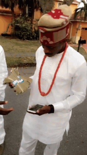 A Man Wearing A White Shirt And A Red Necklace Is Holding A Bunch Of Money GIF