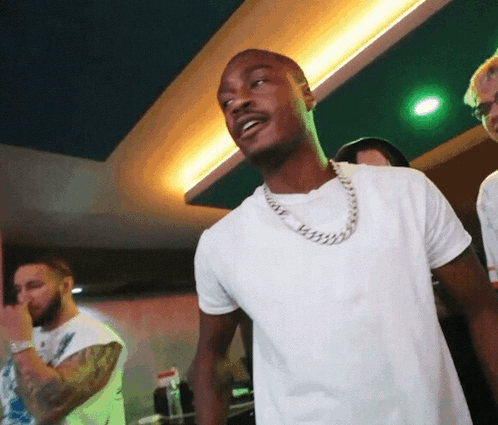 A Man Wearing A White Shirt And A Silver Chain Around His Neck GIF