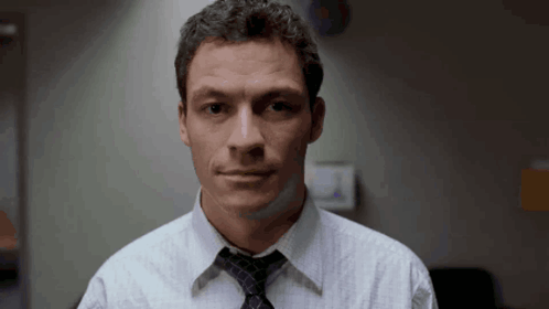 A Man Wearing A White Shirt And A Tie Looks At The Camera GIF