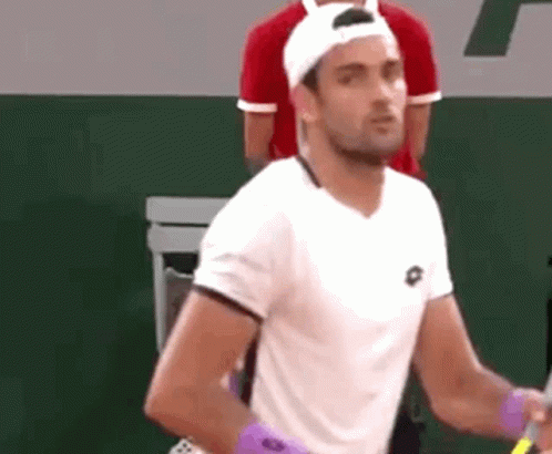 A Man Wearing A White Shirt And A White Hat Is Holding A Tennis Racket . GIF