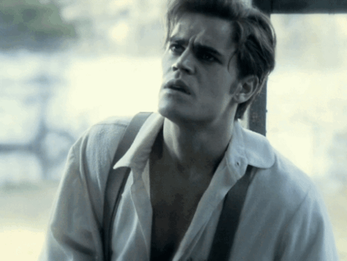 A Man Wearing A White Shirt And Suspenders Looks To The Side GIF