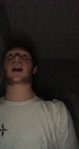 A Man Wearing A White Shirt With A Black Cross On It GIF