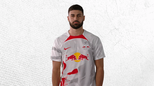 A Man Wearing A White Shirt With A Red Bull On The Front GIF