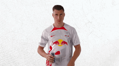 A Man Wearing A White Shirt With Red Bulls On The Front GIF