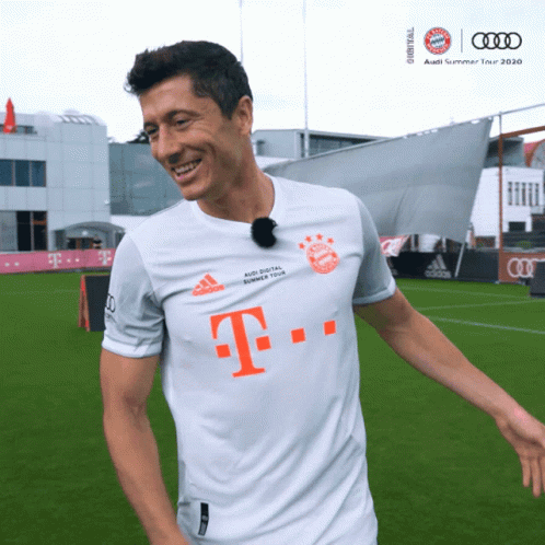 A Man Wearing A White Shirt With The Letter T On The Front GIF
