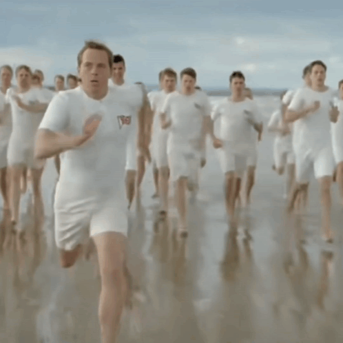 A Man Wearing A White Shirt With The Word England On It Is Running On The Beach GIF