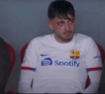 a man wearing a white spotify shirt sits in a chair