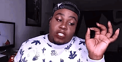 a man wearing a white sweater with a pattern of palm trees and stars is giving the ok sign