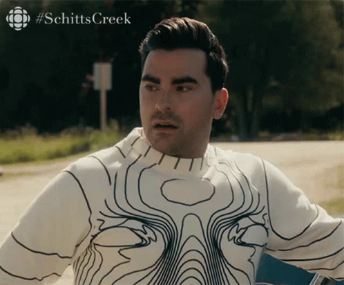 A Man Wearing A White Sweater With Black Lines And The Word Schitts Creek On The Bottom Right GIF