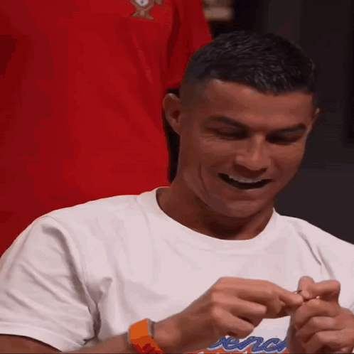 A Man Wearing A White T-Shirt With A Red Shirt Behind Him GIF