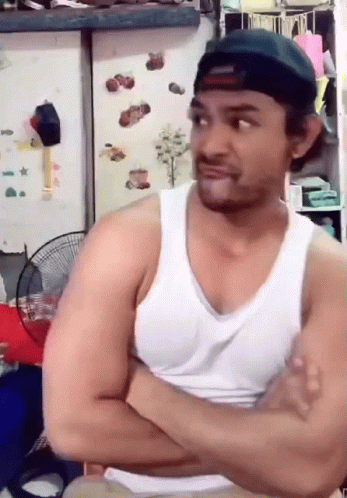 a man wearing a white tank top and a black hat with his arms crossed