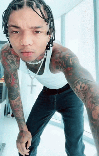 A Man Wearing A White Tank Top And A Necklace With A Cross On It GIF