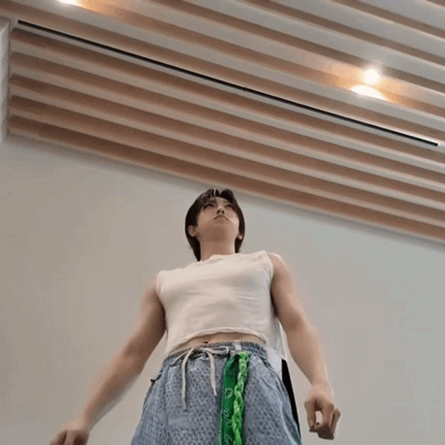 A Man Wearing A White Tank Top And Blue Shorts With A Green Bandana Around His Waist GIF