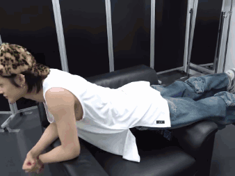 A Man Wearing A White Tank Top And Leopard Print Hat Is Laying On A Couch GIF