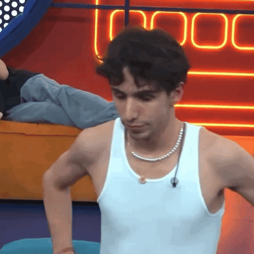 A Man Wearing A White Tank Top And Pearl Necklace GIF