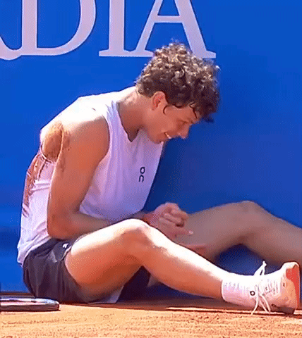 A Man Wearing A White Tank Top With The Word Oc On It Is Sitting On The Ground GIF