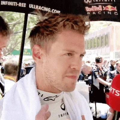 A Man Wearing A White Towel Around His Neck Is Standing In Front Of A Crowd . GIF