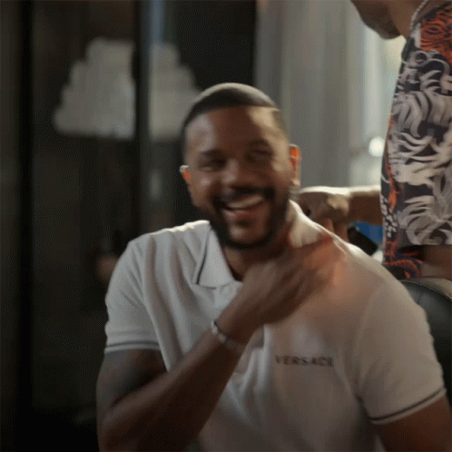 A Man Wearing A White Versace Shirt Laughs GIF