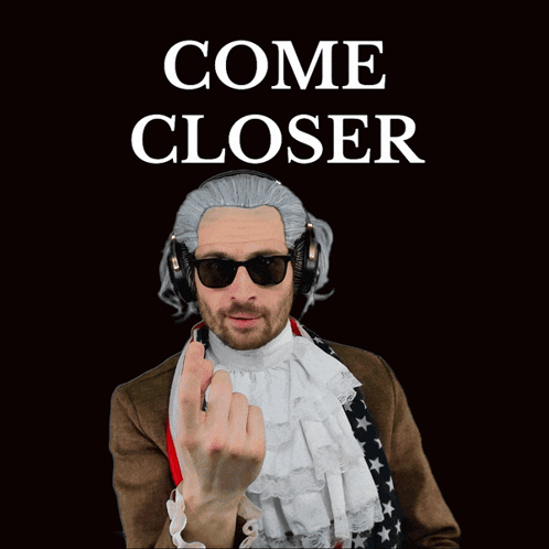 A Man Wearing A Wig And Headphones Has An American Flag Around His Waist GIF