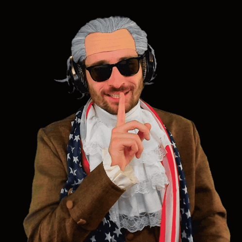A Man Wearing A Wig And Sunglasses Has His Finger To His Mouth GIF