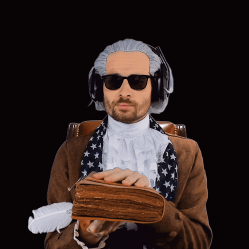 A Man Wearing A Wig And Sunglasses Is Holding A Book And A Feather GIF