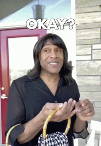 A Man Wearing A Wig Is Holding A Purse And The Word Okay Is Above Him GIF