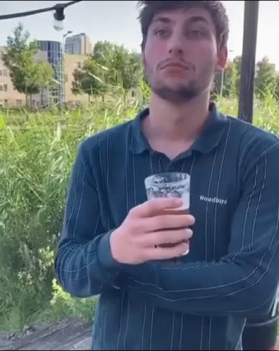 A Man Wearing A Woodbird Shirt Is Holding A Glass Of Beer . GIF