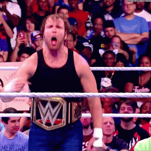 A Man Wearing A Wrestling Belt With The Letter W On It Stands In A Ring GIF