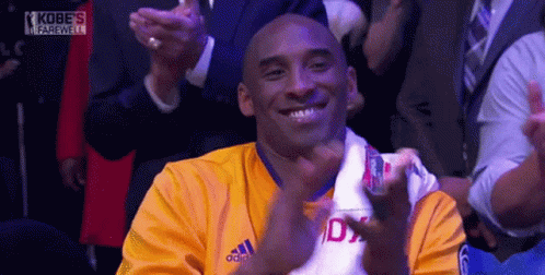 a man wearing a yellow adidas shirt is smiling and applauding