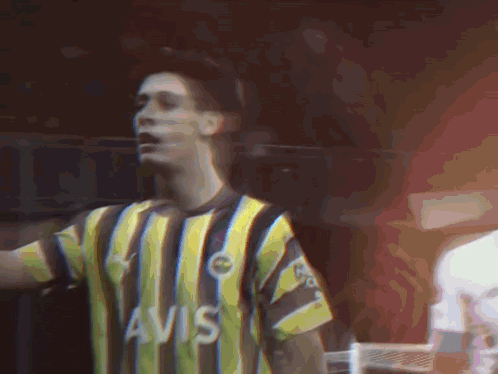 A Man Wearing A Yellow And Black Striped Shirt That Says Avis On It GIF
