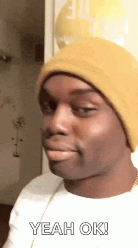 A Man Wearing A Yellow Beanie Is Making A Funny Face And Saying `` Yeah Ok '' . GIF