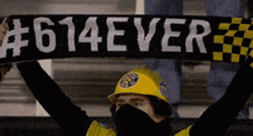 A Man Wearing A Yellow Hard Hat Holds Up A Scarf That Says # 614Ever GIF