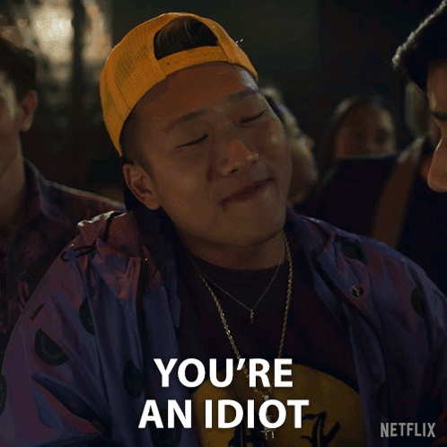 A Man Wearing A Yellow Hat And A Purple Jacket Says " You 'Re An Idiot " GIF