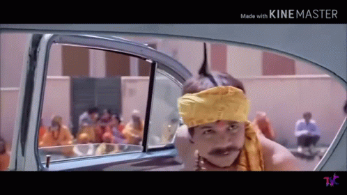 A Man Wearing A Yellow Headband And A Mustache Is Sitting In The Back Of A Car . GIF