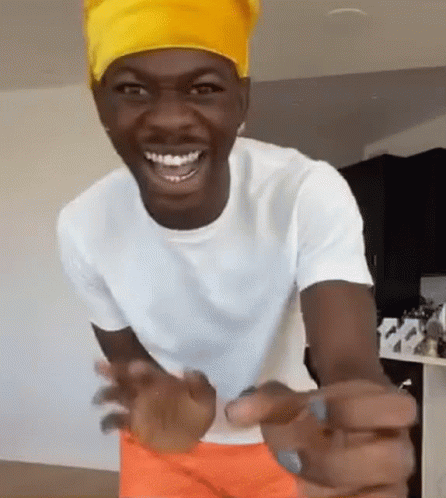 A Man Wearing A Yellow Headband Is Smiling And Pointing At The Camera GIF