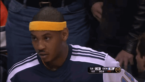 A Man Wearing A Yellow Headband Sits In The Stands During A Basketball Game GIF